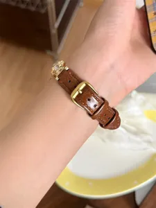 Montre bracelet en cuir marron pour femme avec boucle doree et decoration animale.