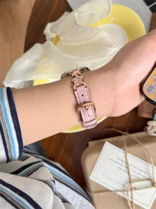 Gros plan détaillé du bracelet de montre en cuir rose élégant orné de charms en zircon étoile.