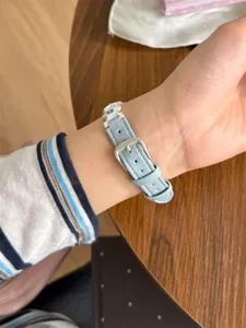 Gros plan d'un bracelet de montre en cuir véritable bleu clair avec boucle et breloques.