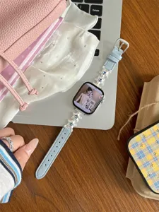 Vue détaillée en gros plan du bracelet de montre en cuir bleu clair avec des charms étoiles.