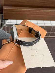 Vue détaillée du bracelet de montre en cuir noir avec étoiles blanches et boucle argentée.