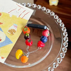 Dettaglio del cinturino per orologio in resina colorata con graziosi ciondoli di frutta in miniatura.