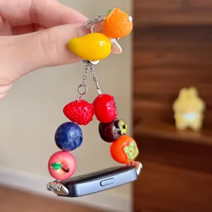 Dettaglio cinturino orologio in resina con frutta colorata e perle in miniatura carine.