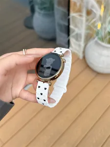 Close-up detail of white silicone smartwatch replacement strap with black heart patterns.