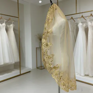 Détail de voile de mariée à sequins dorés avec bordure en dentelle brodée et tulle champagne.