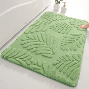Détail de tapis de bain touffeté en feuille verte, texture peluche douce et envers antidérapant.