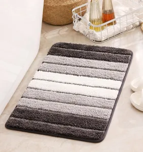 Close-up detail shot of the striped absorbent bathroom floor mat in a modern tile setting.