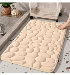 Detail view of beige memory foam bath mat featuring a soft 3D pebble massage texture.