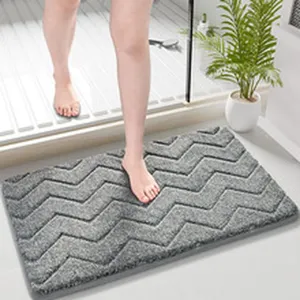 Vista dettagliata del tappeto da bagno grigio con motivo chevron e morbida texture in peluche.
