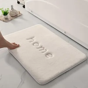 Vue détaillée du tapis de bain en mousse douce avec texte home brodé pour la salle de bain.