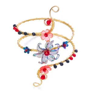 Exquisita pulsera de brazo en espiral de alambre dorado hecha a mano con flores y cuentas.