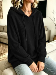 Detailaufnahme des schwarzen Strick-Hoodies mit Tunnelzug, weiche Textur und bequemer Sitz.