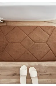 Close-up detail of soft brown memory foam bath mat with textured geometric pattern for floor.