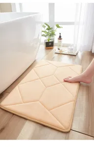 Detailed view of soft memory foam absorbent bath mat with geometric pattern on wooden floor.