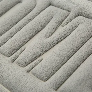 Tappeto da bagno in memory foam grigio con trama peluche goffrata, design antiscivolo.