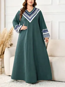 Detail view of plus size long sleeve maxi dress in dark green with geometric print V-neck design.