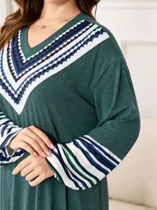 Close-up of the green V-neck dress featuring geometric printed trim and striped long sleeves.