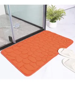 Dettaglio in primo piano del tappetino da bagno antiscivolo arancione con motivo a ciottoli.