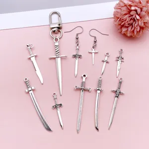 Close-up of antique silver alloy sword charms, dagger pendants, and DIY jewelry accessories.
