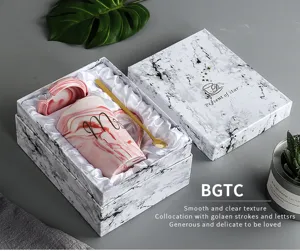 Coffret cadeau tasse en céramique marbrée avec couvercle et cuillère dorée design rose élégant.