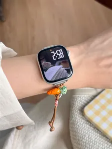 Détail de bracelet de montre en perles tressées en céramique avec charm carotte sur le poignet.