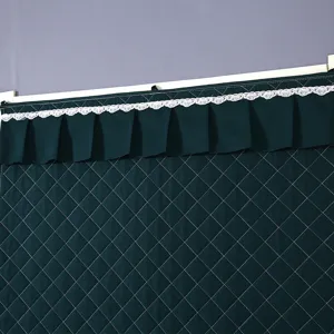Detailed shot of dark green quilted thermal door curtain featuring delicate white lace trim.