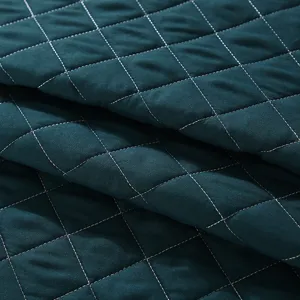 Close up of dark green quilted thermal door curtain fabric detail with neat diamond stitching.