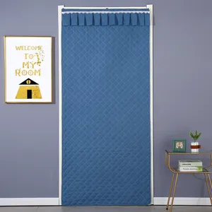 Detailed view of thickened blue quilted door curtain hanging in doorway for thermal insulation.