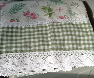 Detailed view of pastoral style short curtain with floral print, green gingham and white lace.