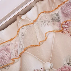 Detalle de la cortina de puerta en encaje con motivo floral de rosas y ribete naranja.