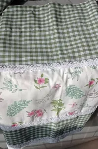 Close-up detail of green checkered floral print half curtain with delicate lace trim.