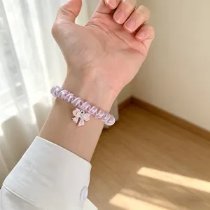 Vista dettagliata di un cinturino per orologio viola chiaro con ciondolo a fiocco rosa.