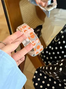 Gros plan detaille de bracelet de montre en silicone a pois oranges, compatible smartwatch, souple.