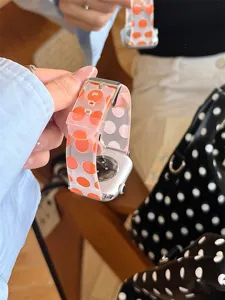 Gros plan detaille du bracelet de montre en silicone transparent a gros pois oranges.