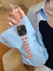 Détail bracelet de montre en silicone transparent, motif à pois orange, matériau souple et flexible.