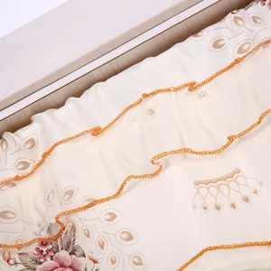 Primer plano detallado de cortina de encaje con estampado floral y borde naranja.