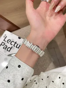 Detailed close-up of a stylish white metal watch strap featuring unique studded links worn on wrist.