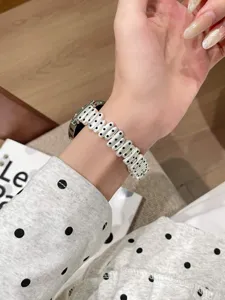 Close-up detail of stylish black and white polka dot metal watch strap worn on wrist gracefully.