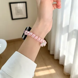 Dettaglio cinturino per orologio a spirale rosa con fiocco, primo piano al polso.