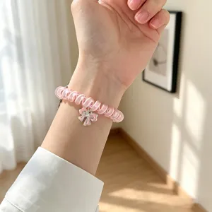 Primo piano del cinturino per orologio in filo telefonico rosa con grazioso ciondolo a fiocco.