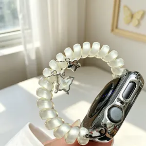 Gros plan détaillé d'un bracelet de montre téléphonique nacré avec des charms papillon et étoile.