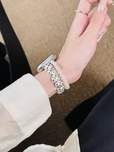 Détail d'un bracelet de montre élégant à double rangée de perles, avec des perles métalliques chics.