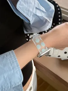 Détail de bracelet de montre en silicone TPU transparent avec des pois bleu clair au poignet.