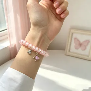 Vue détaillée du bracelet de montre rose en fil téléphonique avec de charmants pendentifs.