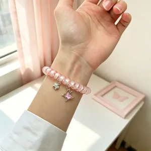 Vue rapprochée du magnifique bracelet de montre téléphonique rose avec de jolis pendentifs.