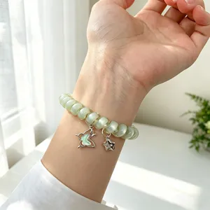 Vue detaillee du bracelet montre fil telephone vert avec charmants pendentifs papillon et etoile.