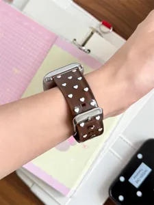 Brown translucent silicone Apple Watch strap with white hearts, soft and stylish design.