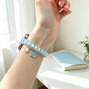 Vue détaillée du bracelet de montre Apple en spirale bleu clair avec pendentif papillon.
