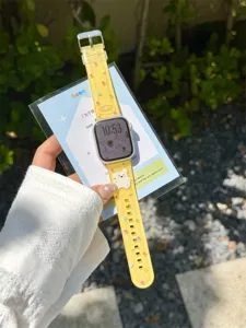 Close-up detail of cute yellow silicone watch strap with colorful polka dots and 3ds bear charm.