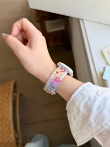 Primo piano di dettaglio di un cinturino in silicone floreale colorato sul polso sottile.